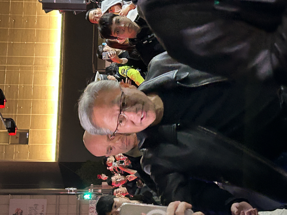Nvidia CEO Jensen Huang takes a selfie with a passerby during a dinner with Samsung Electronics Executive Chairman Lee Jae-yong and Hyundai Motor Group Executive Chair Euisun Chung at a chicken restaurant in southern Seoul on Oct. 30. [SARAH CHEA] 
