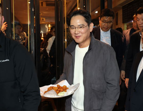 Samsung Electronics Executive Chairman Lee Jae-yong shares chicken with passerbys during a dinner with Nvidia CEO Jensen Huang and Hyundai Motor Group Executive Chair Euisun Chung at a chicken restaurant in southern Seoul on Oct. 30. [JOINT PRESS CORPS] 