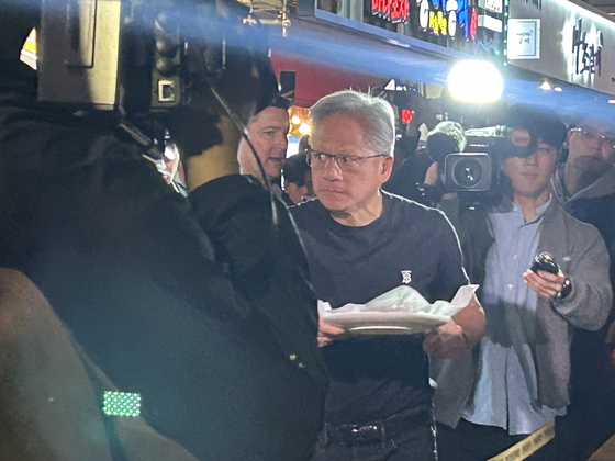 Nvidia CEO Jensen Huang shares chicken and cheese sticks with passersby during a dinner with Samsung Electronics Executive Chairman Lee Jae-yong and Hyundai Motor Group Executive Chair Euisun Chung at a chicken restaurant in southern Seoul on Oct. 30. [SARAH CHEA] 