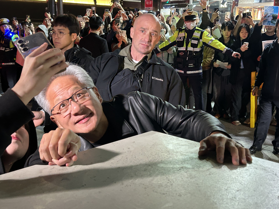 Nvidia CEO Jensen Huang takes a selfie with a passerby during a dinner with Samsung Electronics Executive Chairman Lee Jae-yong and Hyundai Motor Group Executive Chair Euisun Chung at a chicken restaurant in southern Seoul on Oct. 30. [SARAH CHEA] 