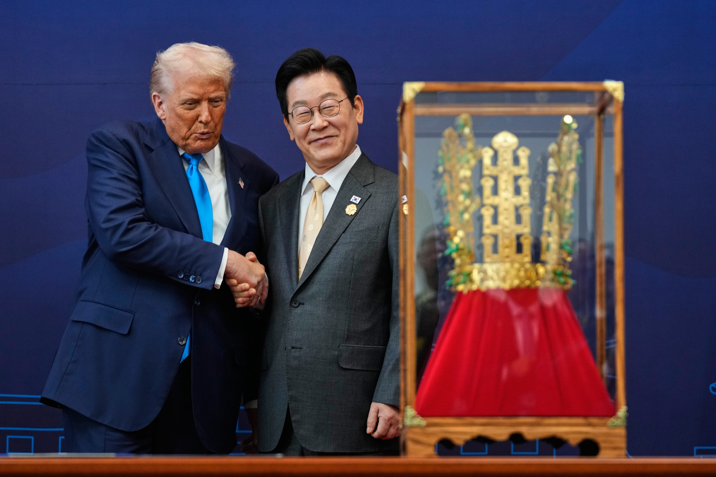U.S. President Donald Trump, left, shakes hands with President Lee Jae Myung as Trump receives a gold crown and the Grand Order of Mugunghwa, not seen, as gifts during a high honor ceremony at the Gyeongju National Museum in North Gyeongsang on Oct. 29. [AP/YONHAP]