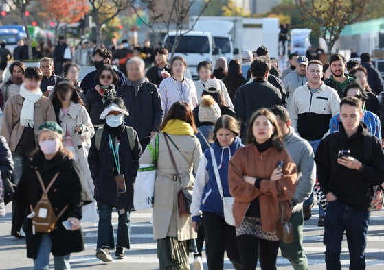 Citizens and tourists walk are seen in heavy clothing in the streets of Gwanghwamun, central Seoul, as temperatures drop on Nov. 2. [YONHAP]