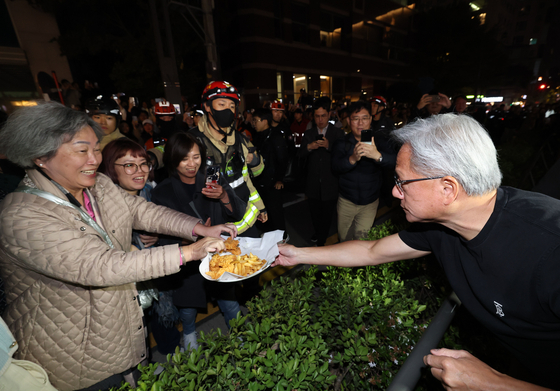 Nvidia CEO Jensen Huang shares chicken and cheese sticks with passerbys during a dinner with Samsung Electronics Executive Chairman Lee Jae-yong and Hyundai Motor Group Executive Chair Euisun Chung at a chicken restaurant in southern Seoul on Oct. 30. [JOINT PRESS CORPS] 