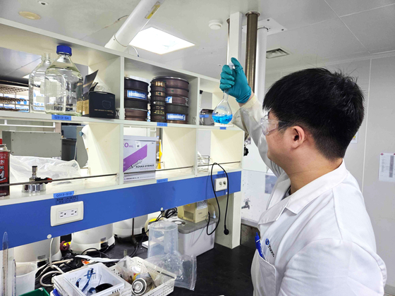Ying Wei Wang inspects samples at a lab. [HUONS]