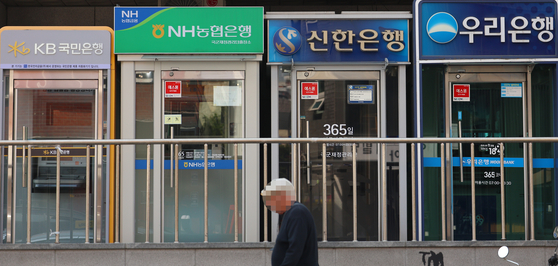 A passerby walks past ATMs in Seoul on April 16. [YONHAP]