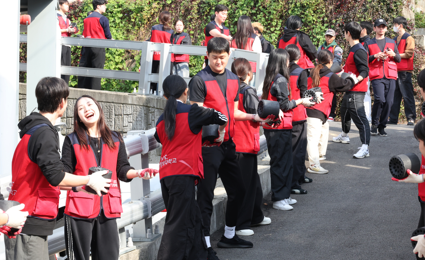 Faculty and students — both Korean and international — from Kyungnam College of Information and Technology deliver coal briquettes to low-income households in Gwaenae Village, Sasang District, Busan, on Nov. 4. [YONHAP]