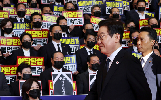 President Lee Jae Myung walks past silent protestors from the conservative People Power Party (PPP) as he arrives at the National Assembly in Yeouido, western Seoul, to deliver a budget speech on Nov. 4. PPP lawmakers hold placards condemning the special counsel’s arrest warrant request for former floor leader Choo Kyung-ho. [JOINT PRESS CORPS] 