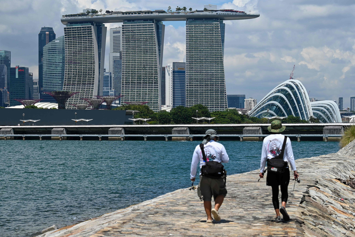 Anglers walk along a breakwater as the Marina Bay Sands and city skyline is seen from Marina East in Singapore on Oct. 14. [AFP/YONHAP]