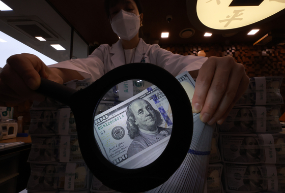 A Hana Bank official checks for fake dollar bills at the Jung District main branch in central Seoul on Nov. 5. [YONHAP]