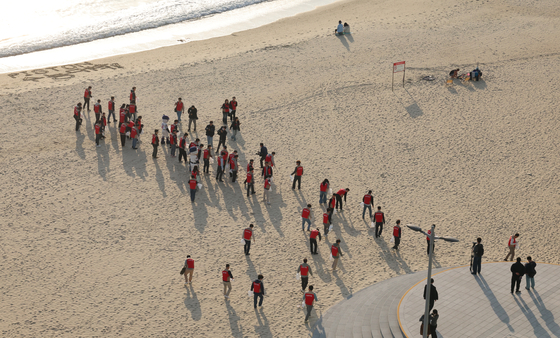 Around 60 employees from 21 Lotte Group affiliates based in Busan, including Lotte Hotel, Lotte Giants, and Lotte Department Store, take part in a beach cleanup activity at Haeundae Beach in Busan on Nov. 5. [YONHAP] 
