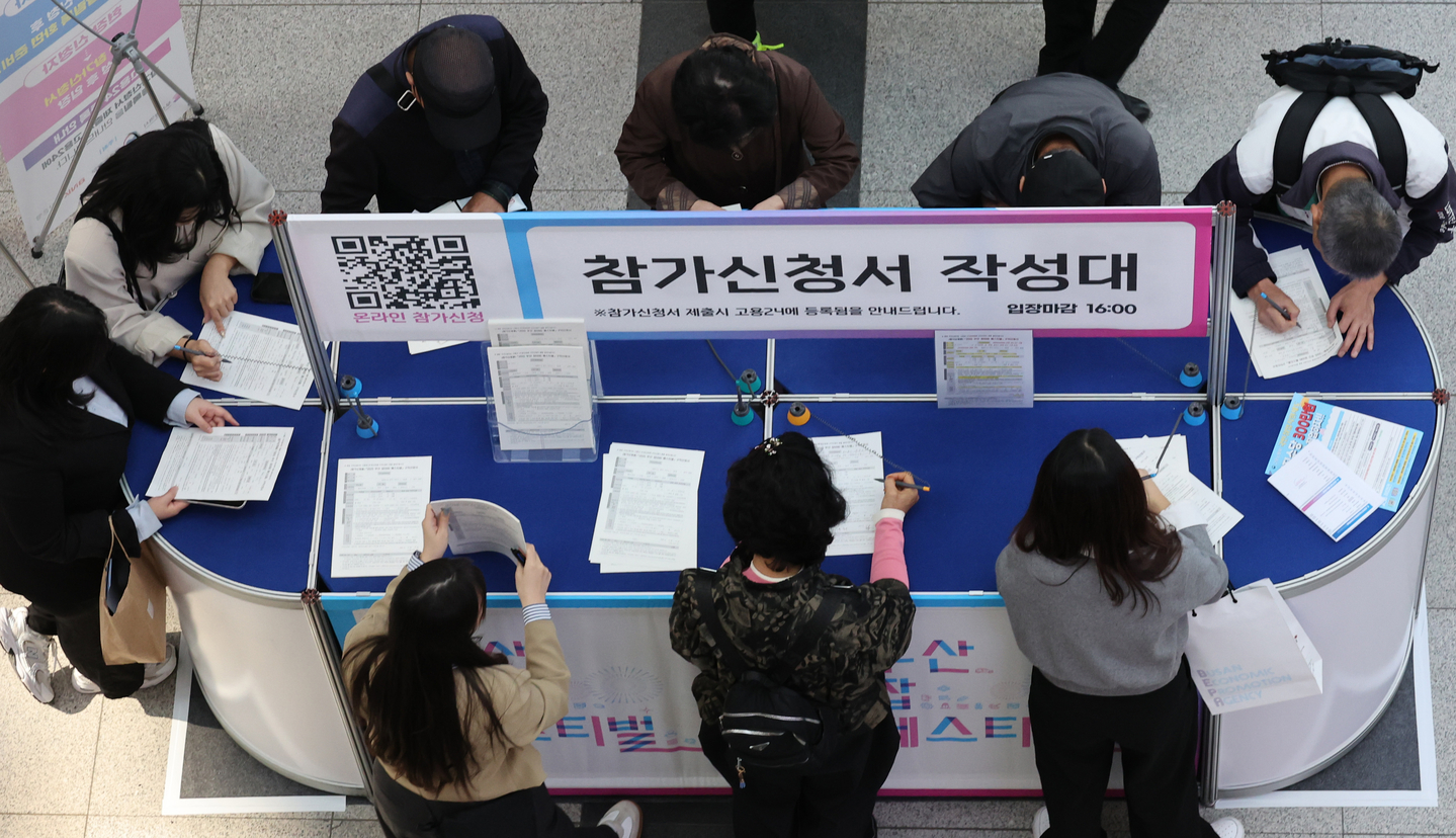 Job seekers fill out forms at the 2025 Busan Job Festival, an event offering employment opportunities for all age groups, at Bexco in Haeundae District, Busan, on Oct. 27. [SONG BONG-GEUN]
