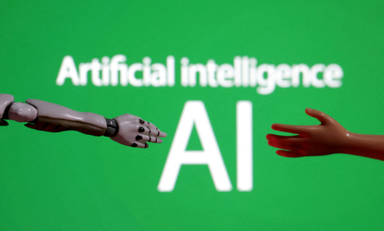 A miniature of a robot and a toy hand are pictured in this illustration taken on Dec. 14, 2023. [REUTERS/YONHAP] 