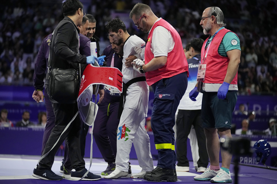 Azerbaijan's Gashim Magomedov is helped by members of his team after being injured in the taekwondo men's -58kg final against Azerbaijan's Gashim Magomedov at the Grand Palais in Paris on Wednesday.  [AP/YONHAP]