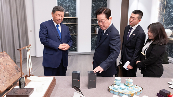 President Lee Jae Myung examines the Xiaomi smartphone presented to him by Chinese President Xi Jinping on Nov. 2. [YONHAP] 