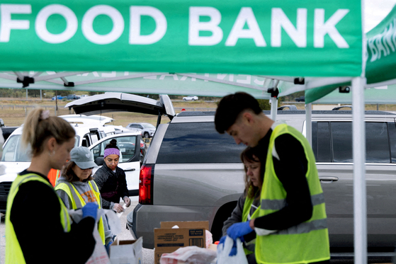 Volunteers place food items in vehicles during a mobile food distribution at Cedar Creek High School, as nearly 42 million Americans face a potential lapse in Supplemental Nutrition Assistance Program (SNAP) benefits, known as food stamps, due to the second-longest U.S. government shutdown, in Cedar Creek, Texas, U.S., Nov. 1. [REUTERS/YONHAP]