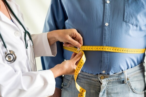 A doctor measures a patient's waist circumference in this file photo. [GETTY IMAGES BANK]