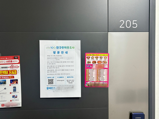 A notice for the 2025 Population and Housing Census is posted alongside various advertisements on the door of a multifamily housing unit in Seoul on Nov. 7. [LEE AH-MI]