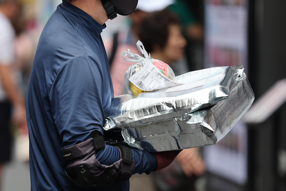 A delivery driver picks up food to be delivered at a restaurant in downtown Seoul on June 29. [YONHAP]