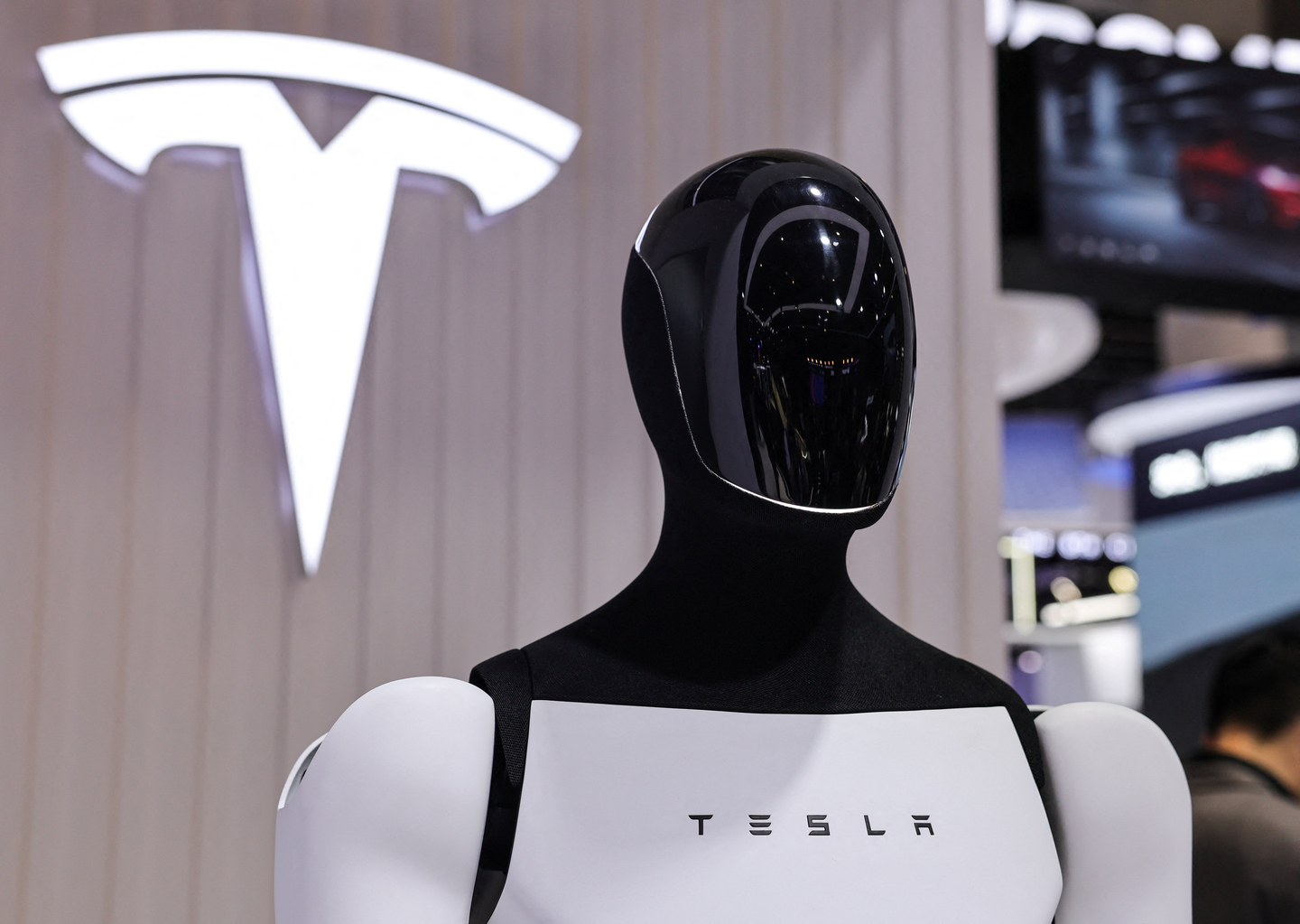 A Tesla Optimus robot is displayed next to a logo at the company’s booth at the 8th China International Import Expo in Shanghai, China, on Nov. 6. [REUTERS/YONHAP]