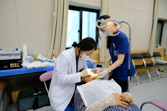A dentist, left, operates on a patient. Photo is not related to the story. [JOONGANG ILBO]