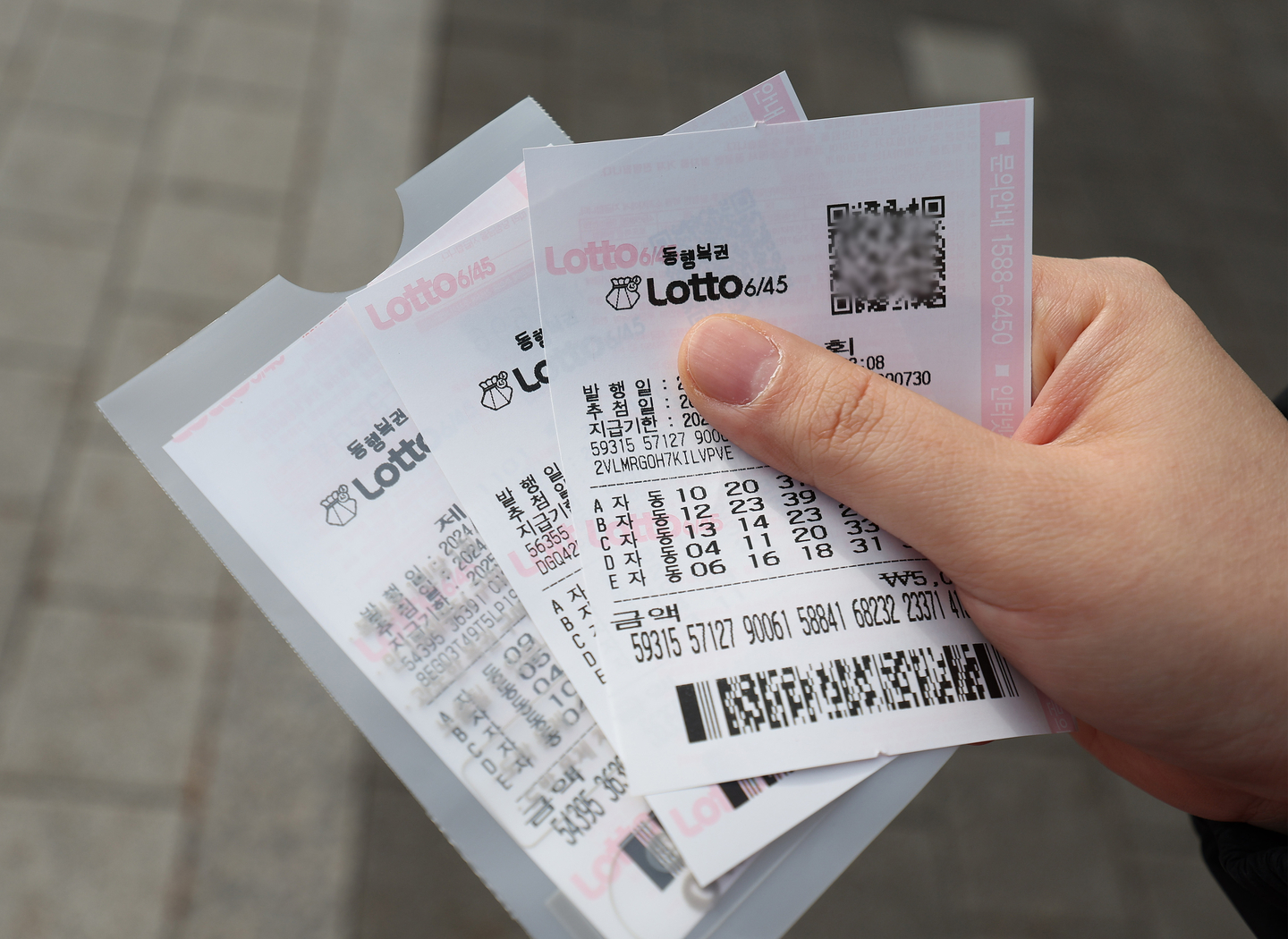 A person holds their lottery ticket in front of a lottery shop in Nowon District, northern Seoul, on Jan. 1, 2024. [YONHAP] 