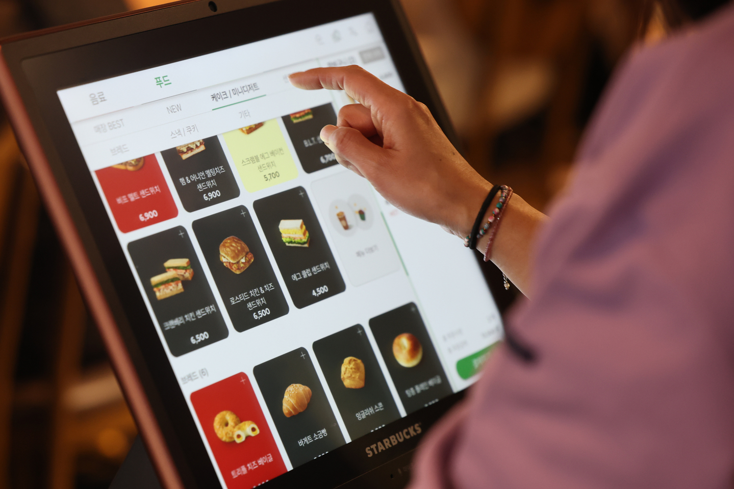A customer places an order at a kiosk inside Starbucks Myeongdong-gil store in Jung District, central Seoul, on Nov. 16. Starbucks Korea announced that it will introduce unmanned ordering machines on a trial basis at about 20 stores in areas with high foreign tourist or general foot traffic, including Myeongdong, Jongno and Gangnam districts and Jeju. It is the first time that Starbucks has launched kiosk ordering systems in Korea. [YONHAP]
