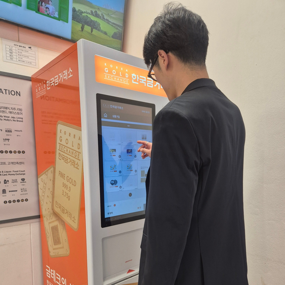 An office worker tries to buy gold from a vending machine.[JOONGANG ILBO]