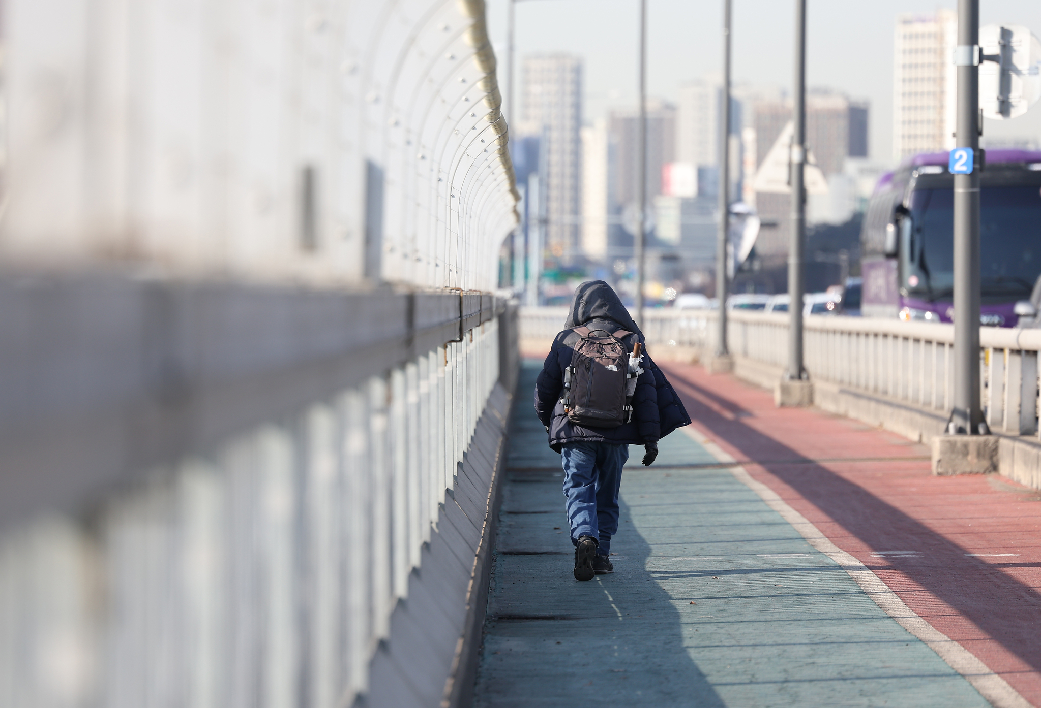 A pedestrian walks next to a high fence intended to stop people from jumping on Mapo Bridge in Seoul on Feb. 27. [YONHAP] 