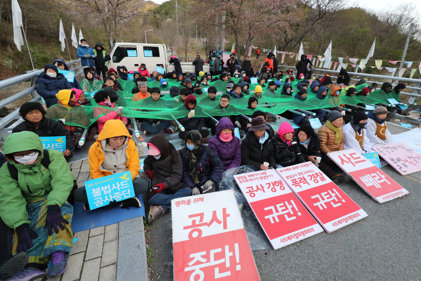 Anti-Thaad activists and local residents sit down on the Jinbat Bridge in Soseong-ri, Chojeon-myeon, Seongju County, North Gyeongsang, on the morning of April 12, 2018, to block access. [NEWS1]