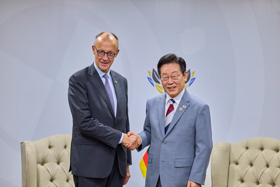 President Lee Jae Myung, right, and German Chancellor Friedrich Merz shake hands during a summit at the Johannesburg Expo Centre in Johannesburg, South Africa on Nov. 22. [YONHAP] 