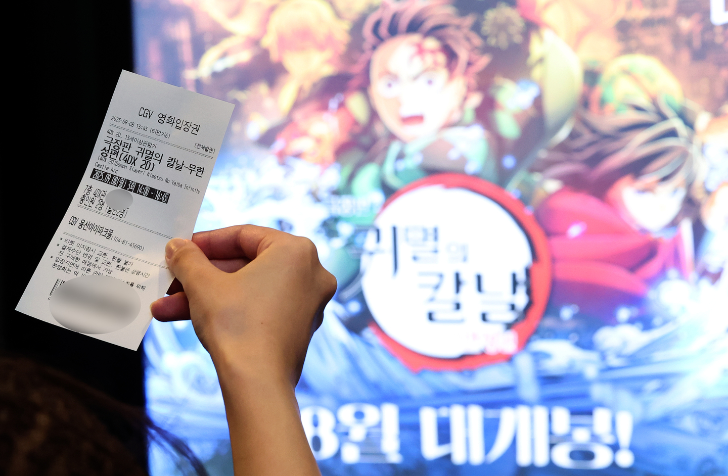 A person holds a movie ticket in front of a poster of Japanese animated film ″Demon Slayer: Kimetsu no Yaiba — The Movie: Infinity Castle″ at a theater in Seoul on Sept. 8. [NEWS1]