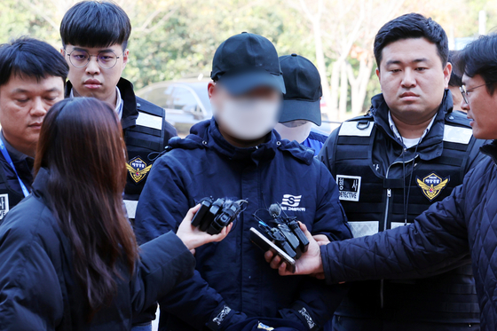 The first mate, center, accused of accidentally grounding a ferry carrying 246 passengers and 21 crew members off the southeast coast early this week, answers questions from reporters at the Gwangju District Court's Mokpo branch on Nov. 22. [YONHAP]