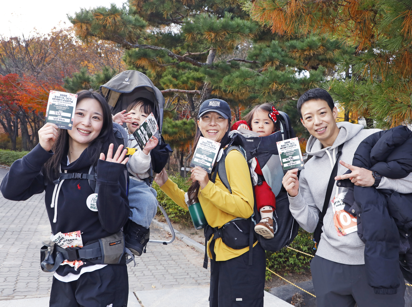 Participants of the 2025 Seoul Eco Hiking Festa pose for a photo with their completion certificates, carrying their children after hiking along a trail on Mount Namsan in Jung District, central Seoul, during the event’s family-themed hike on Nov. 22. [PARK SANG-MOON]