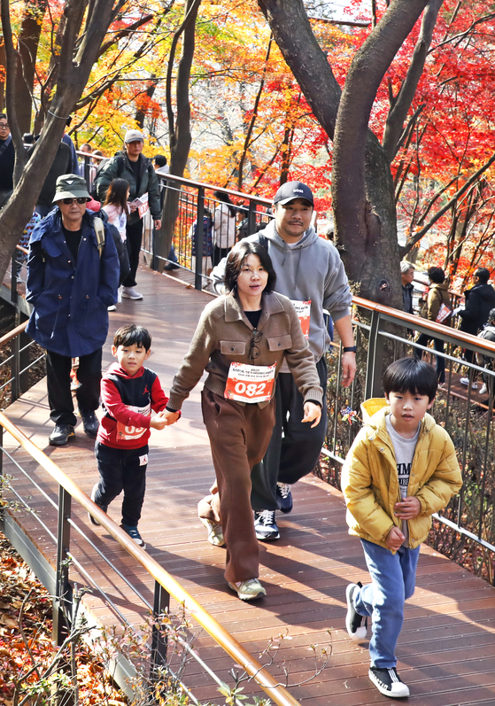 A family walks along a trail on Mount Namsan in Jung District, central Seoul, during the 2025 Seoul Eco Hiking Festa's family-themed hike on Nov. 22. [PARK SANG-MOON]