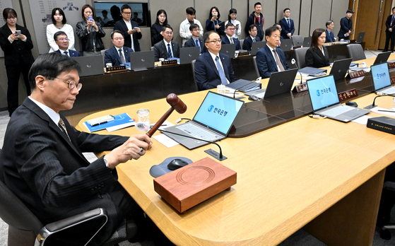 Bank of Korea Gov. Rhee Chang-yong, left, bangs the gavel to open a Monetary Policy Committee meeting at the central bank in Seoul, in this file photo from Oct. 23. [YONHAP]