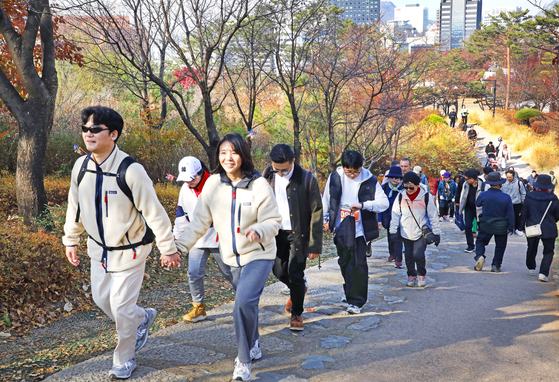 Participants of the 2025 Seoul Eco Hiking Festa walk along a trail on Mount Namsan in Jung District, central Seoul, during the event’s family-themed hike on Nov. 22. [PARK SANG-MOON]
