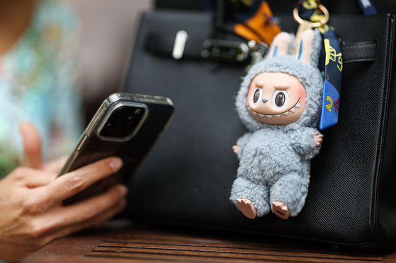 A Labubu key ring doll hangs on a handbag. [TASS]