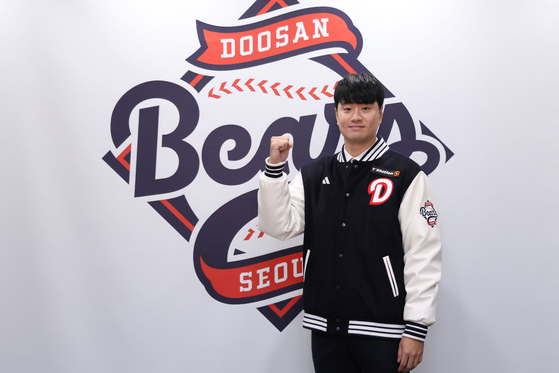 Doosan Bears pitcher Lee Young-ha poses in front of the club's logo at Jamsil Baseball Stadium in southern Seoul after signing a new four-year contract with the club on Nov. 27. [YONHAP]