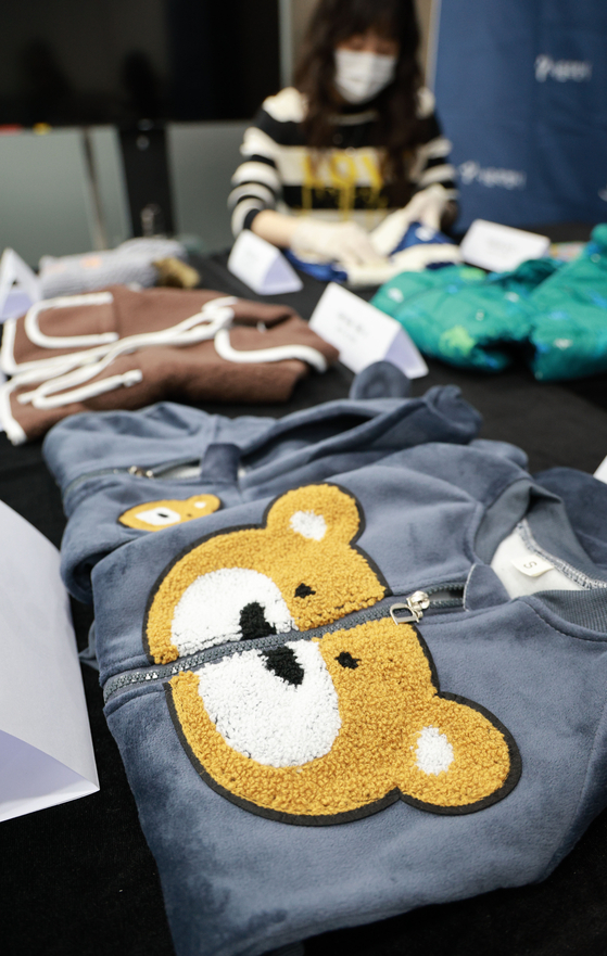A government official inspects children’s winter clothing and accessories that fail to meet domestic safety standards at Seoul City Hall on Nov. 27. The Seoul Metropolitan Government announced that a survey of 24 children’s winter clothing and accessories sold on overseas online platforms found that eight of them did not comply with Korea’s safety regulations. [YONHAP] 