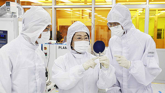 Gachon University President Lee Gil-ya, center, holds a wafer at the Nanofab Center on the first floor of the university’s College of Semiconductor. [GACHON UNIVERSITY]