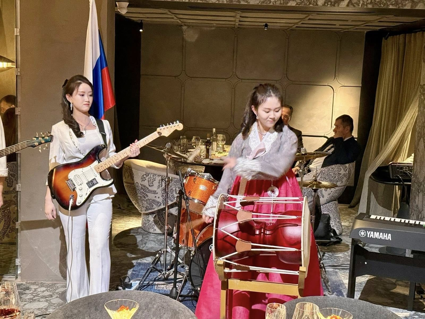 A woman wearing hanbok (traditional Korean dress) plays the janggu (traditional drum) while a woman in a suit plays the guitar at a newly opened North Korean restaurant in Moscow, Russia, on Nov. 26 in this photo uploaded to Facebook by the Russian Embassy to North Korea on Nov. 28. [RUSSIAN EMBASSY IN THE DPRK]