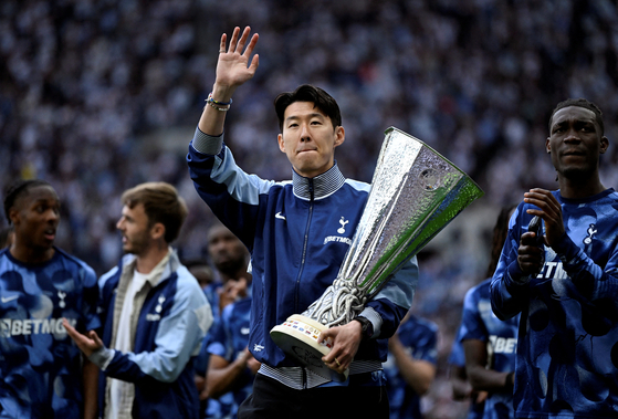 Tottenham Hotspur captain Son Heung-min waves to fans whilst holding the Europa League trophy during the lap of appreciation at Tottenham Hotspur Stadium in London on May 25. [REUTERS/YONHAP]
