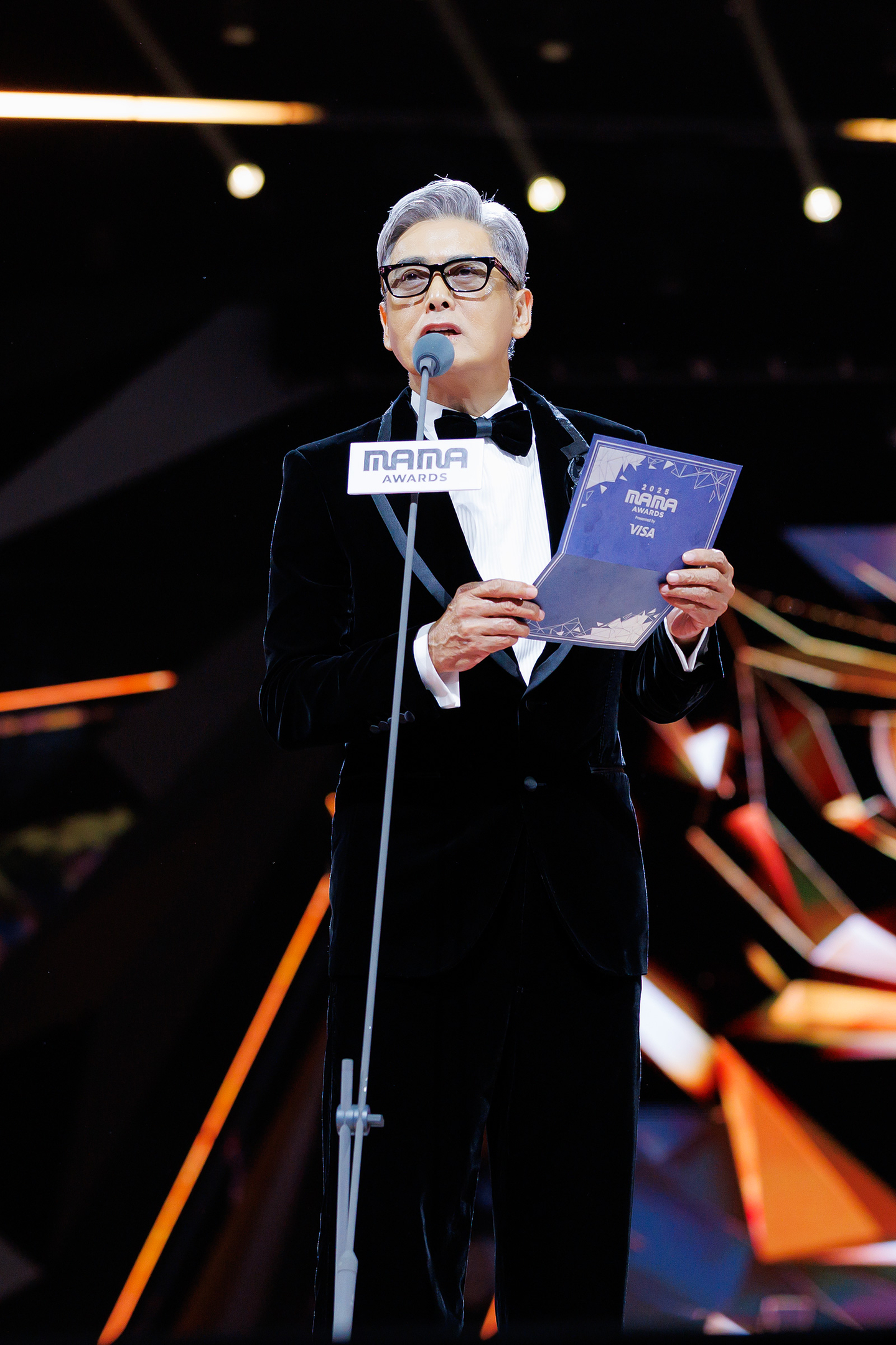 Hong Kong actor Chow Yun-fat asks everyone in the 2025 MAMA Awards venue to rise for a moment of silence to mourn the deaths of victims in a major fire in Hong Kong. [CJ ENM]