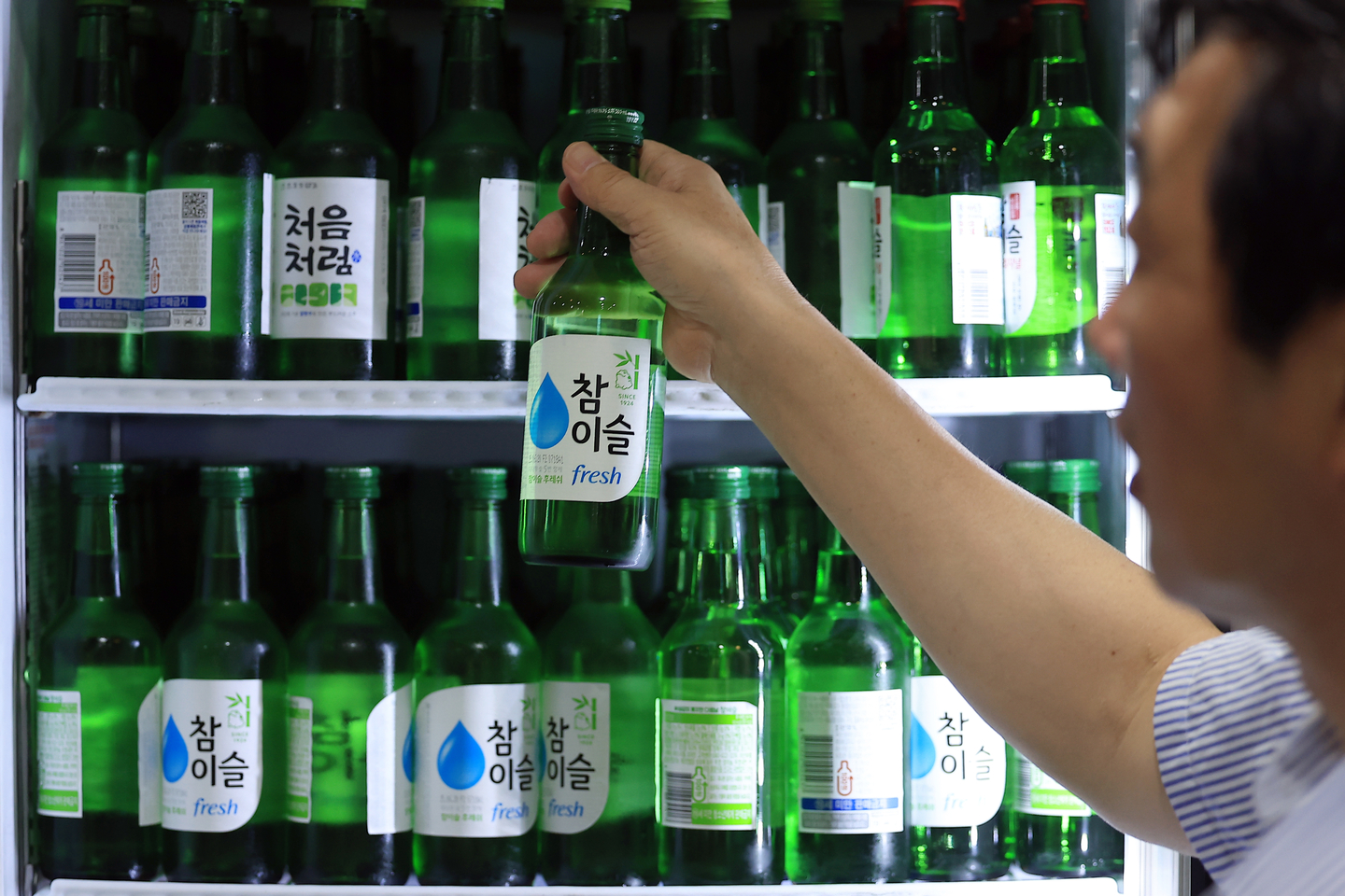 A worker picks up a bottle of soju at a restaurant in Jongno District, central Seoul, on July 8. [NEWS1]