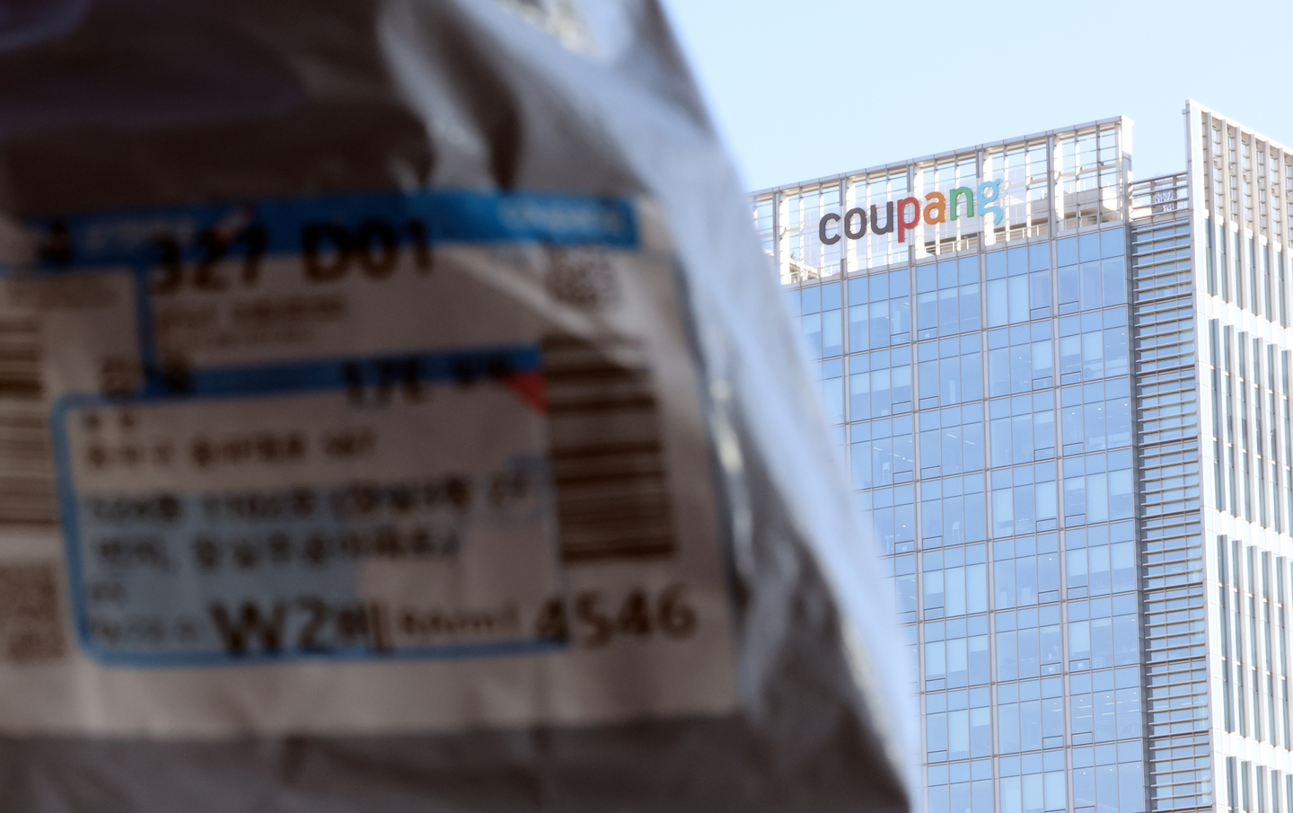 A Coupang delivery parcel is seen with the Coupang headquarters logo in the background, in Songpa District, southern Seoul, on Dec. 1. [YONHAP]