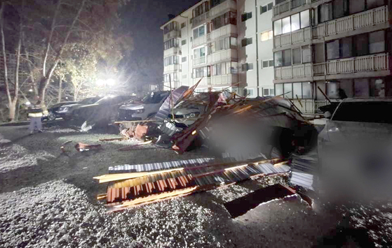 Cars are seen damaged at an apartment complex in Sokcho, Gangwon, after a section of roofing blown loose by strong winds fell to the parking lot on the morning of Dec. 1. [YONHAP]