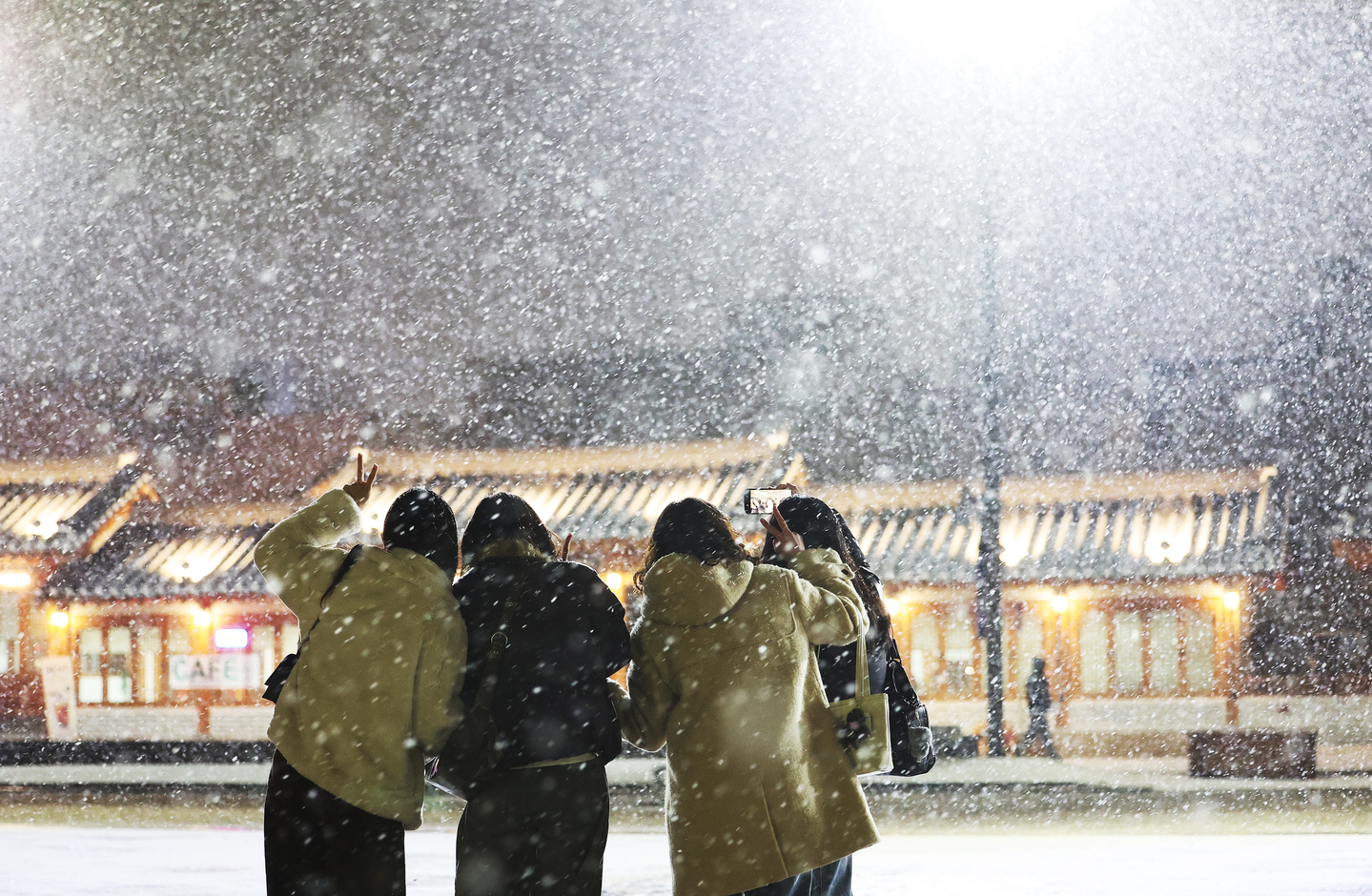 Passersby capture the season’s first snowfall at Hwaseong Haenggung Square in Suwon, Gyeonggi, on Dec. 4. [YONHAP]