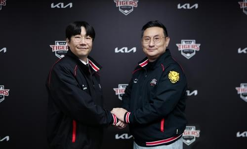 Kia Tigers pitcher Yang Hyeon-jong, left, shakes hands with the club's general manager, Shim Jae-hak, after signing a new deal with the Tigers on Dec. 4. [YONHAP]
