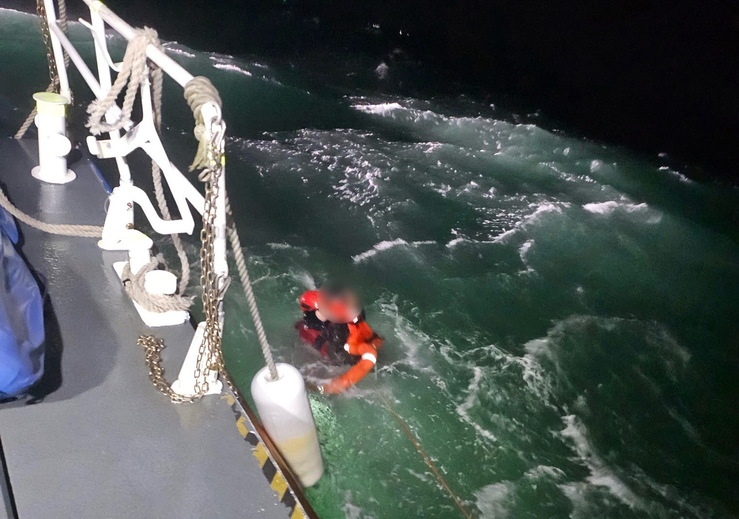 A Coast Guard officer rescues a crew member who fell into the sea after a fishing boat capsized near Cheollipo, Taean County, South Chungcheong, at around 6:20 p.m. on Dec. 4. [TAEAN COAST GUARD]