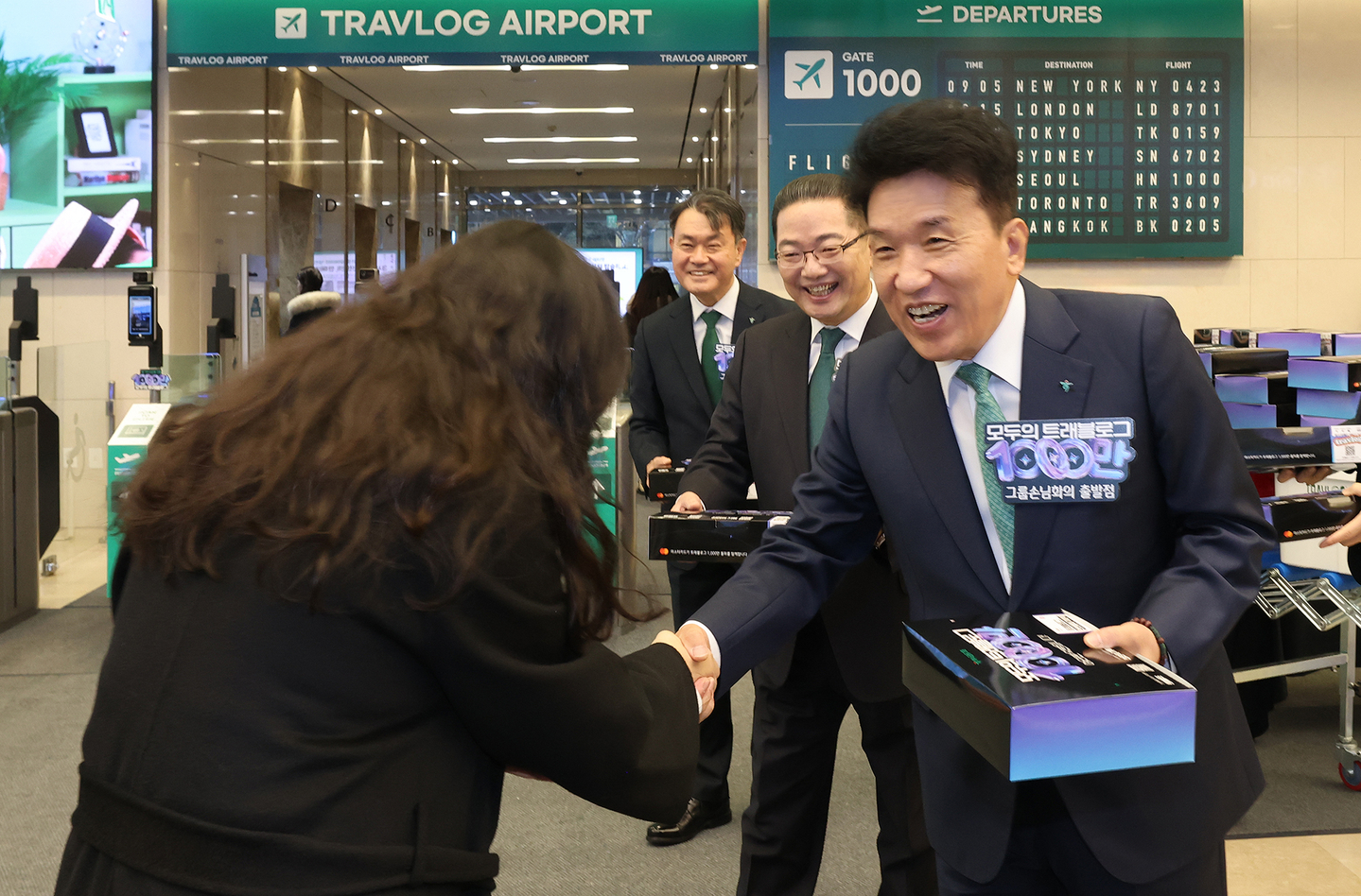 Hana Financial Group celebrates the Travlog platform surpassing 10 million subscribers with a commemorative event on Dec. 5 at Hana Bank’s Euljiro headquarters in central Seoul. At the event, Hana Financial Group Chairman Ham Young-joo, right, hands out limited-edition “in-flight meals” themed after the Travlog service to employees arriving at work as a gesture of appreciation. [HANA FINANCIAL GROUP]